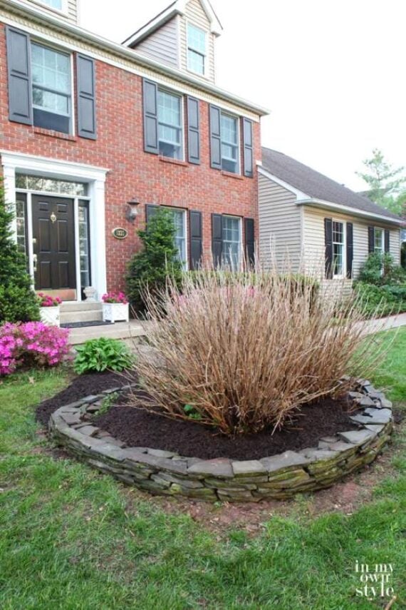 Curving gravel garden path surrounded by stone borders and purple flowering plants