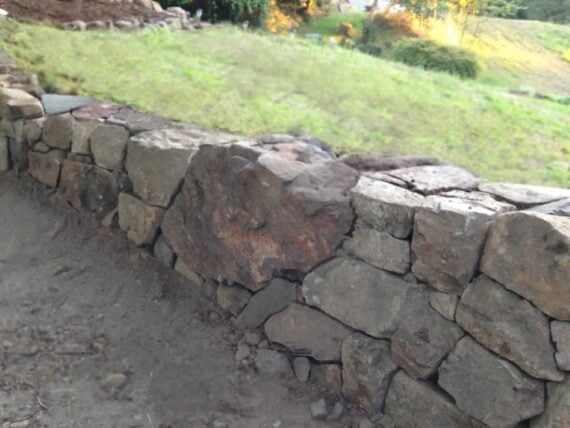 DIY stone retaining wall built with large natural rocks