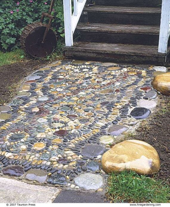 Pebble mosaic garden path with decorative stone patterns near porch steps