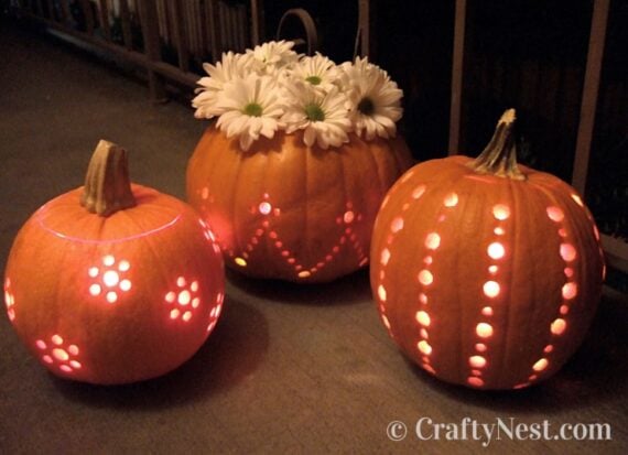 Pumpkins carved with bright polka dots and floral motifs, one used as a flower vase.