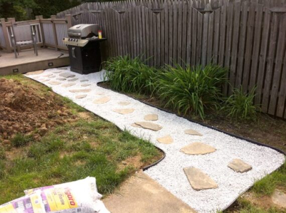 Backyard gravel path with large stepping stones next to wooden fence