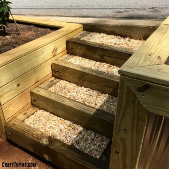 Wooden garden stairs filled with pea gravel between raised beds