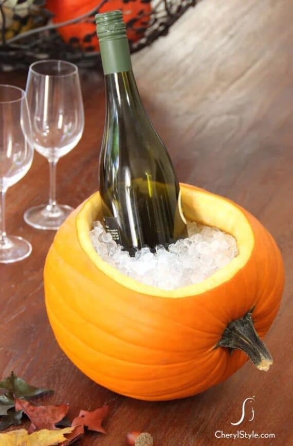 Carved pumpkin used as a cooler, filled with ice and a bottle of wine.