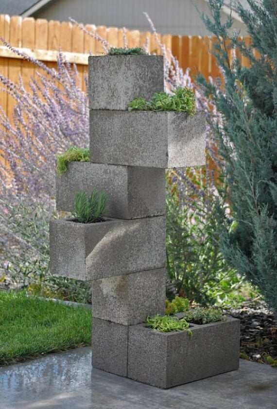 Stacked concrete cinder blocks with succulents growing from the openings