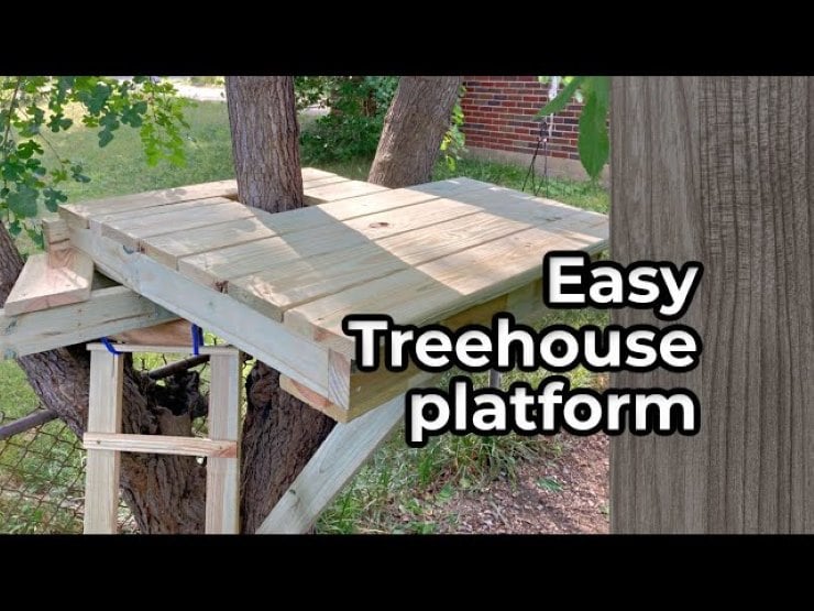 Simple DIY treehouse platform built between tree trunks with wooden beams and ladder support.