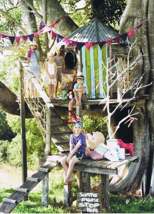 Colorful DIY Multi-Level Backyard Treehouse with Stairs, Deck and Frame Decorations.